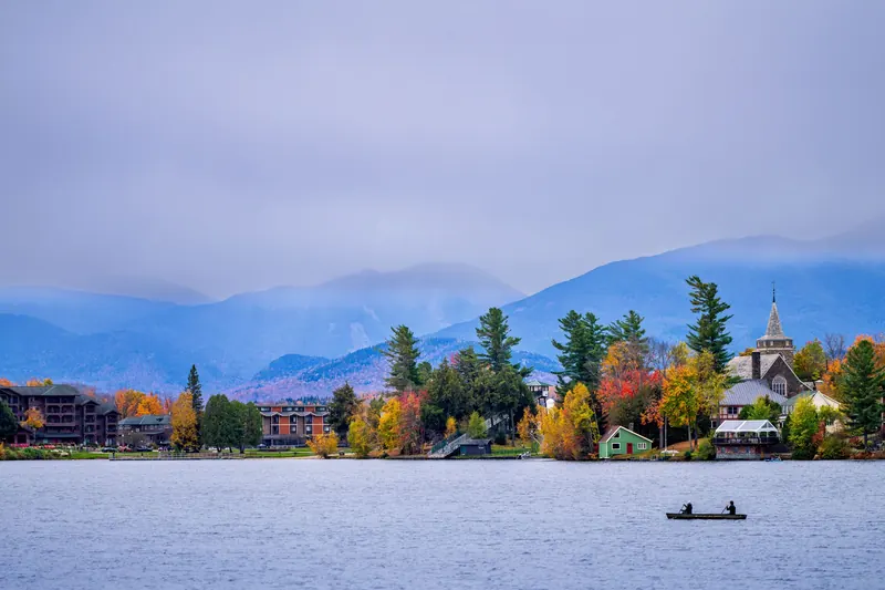 Mirror Lake in Lake Placid ringed by autumn trees, with Adirondack peaks behind