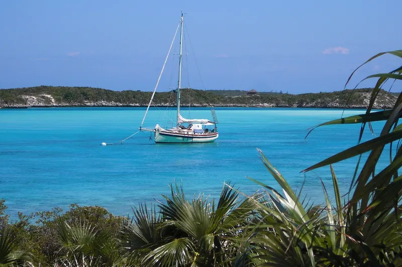 A sailboat anchored in turquoise water off a cay in the Exumas, Bahamas