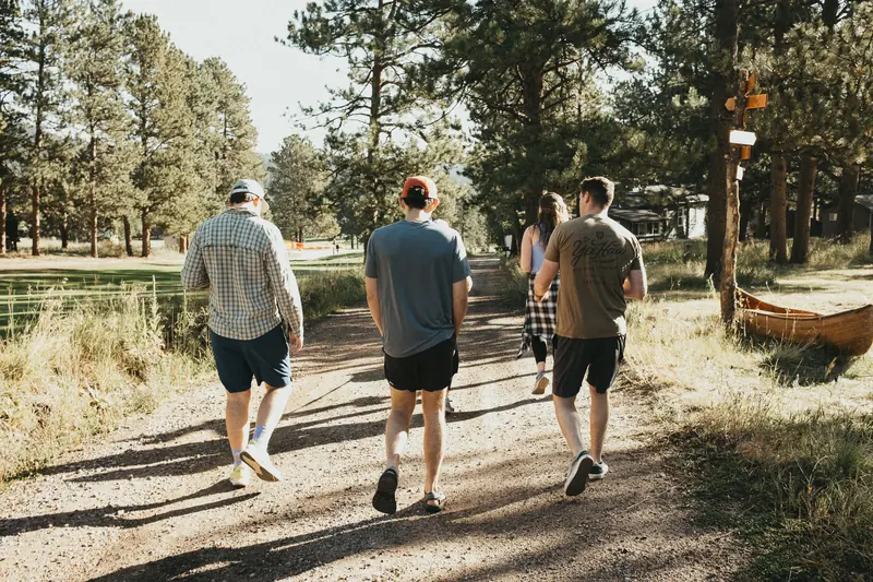 Four colleagues walking a sunny forest trail in Colorado
