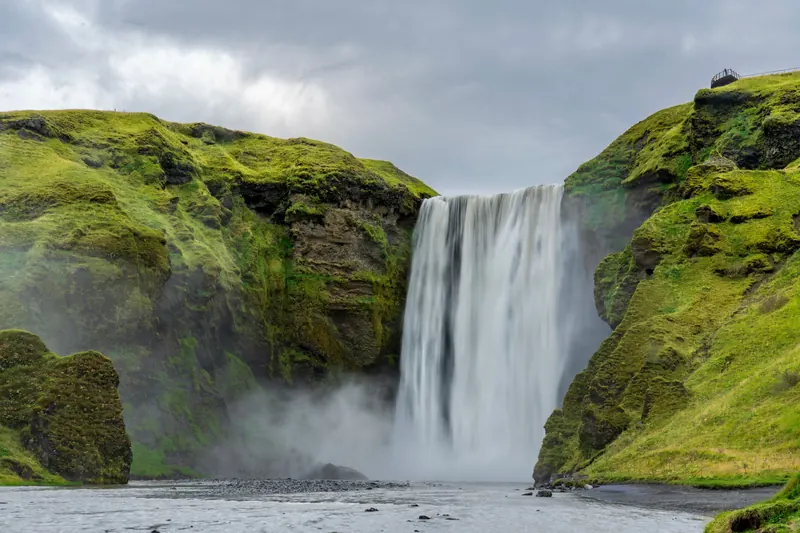 Skógafoss waterfall between green cliffs on Iceland's south coast
